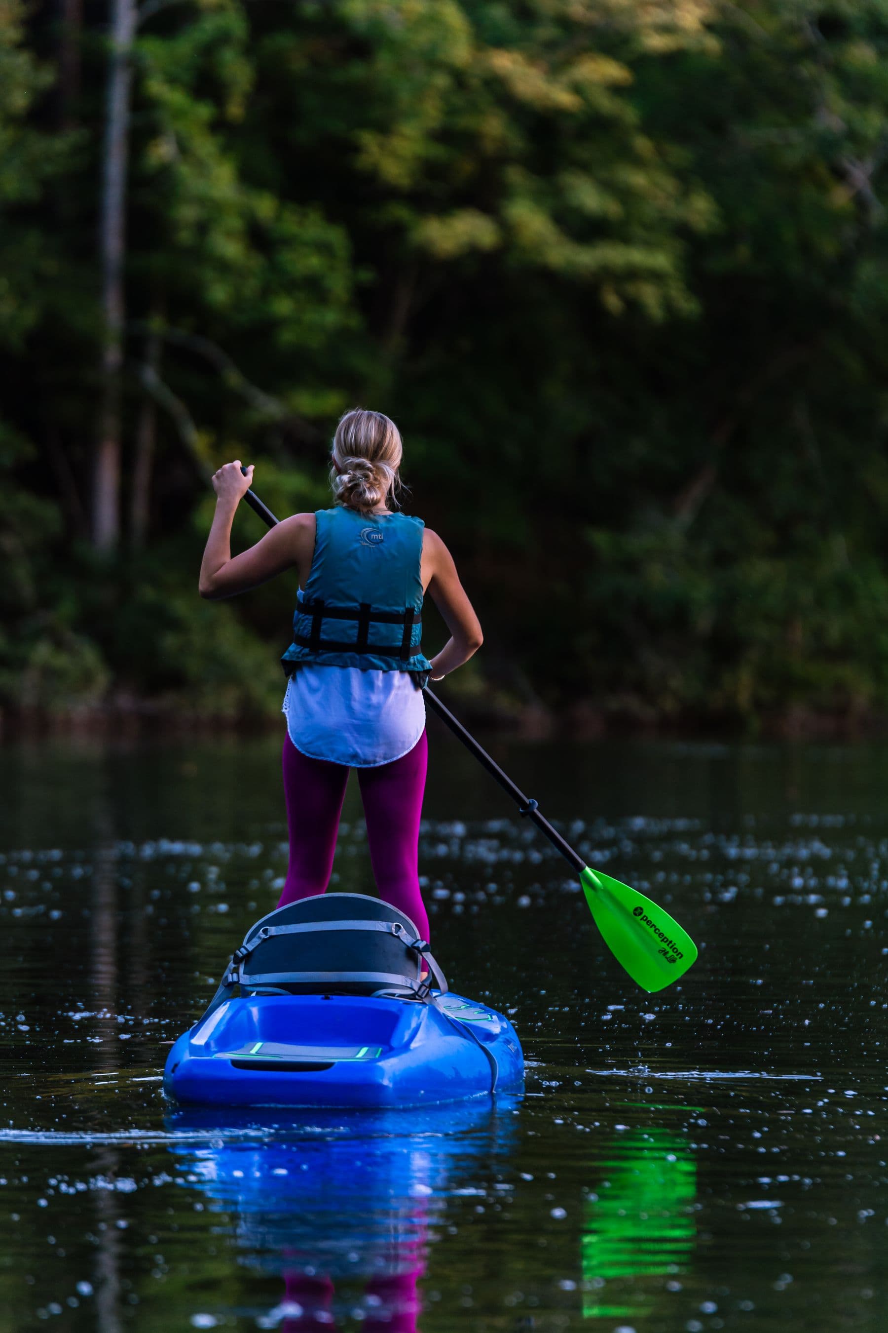 Personne sur un paddle, sur une eau calme bordee de verdure